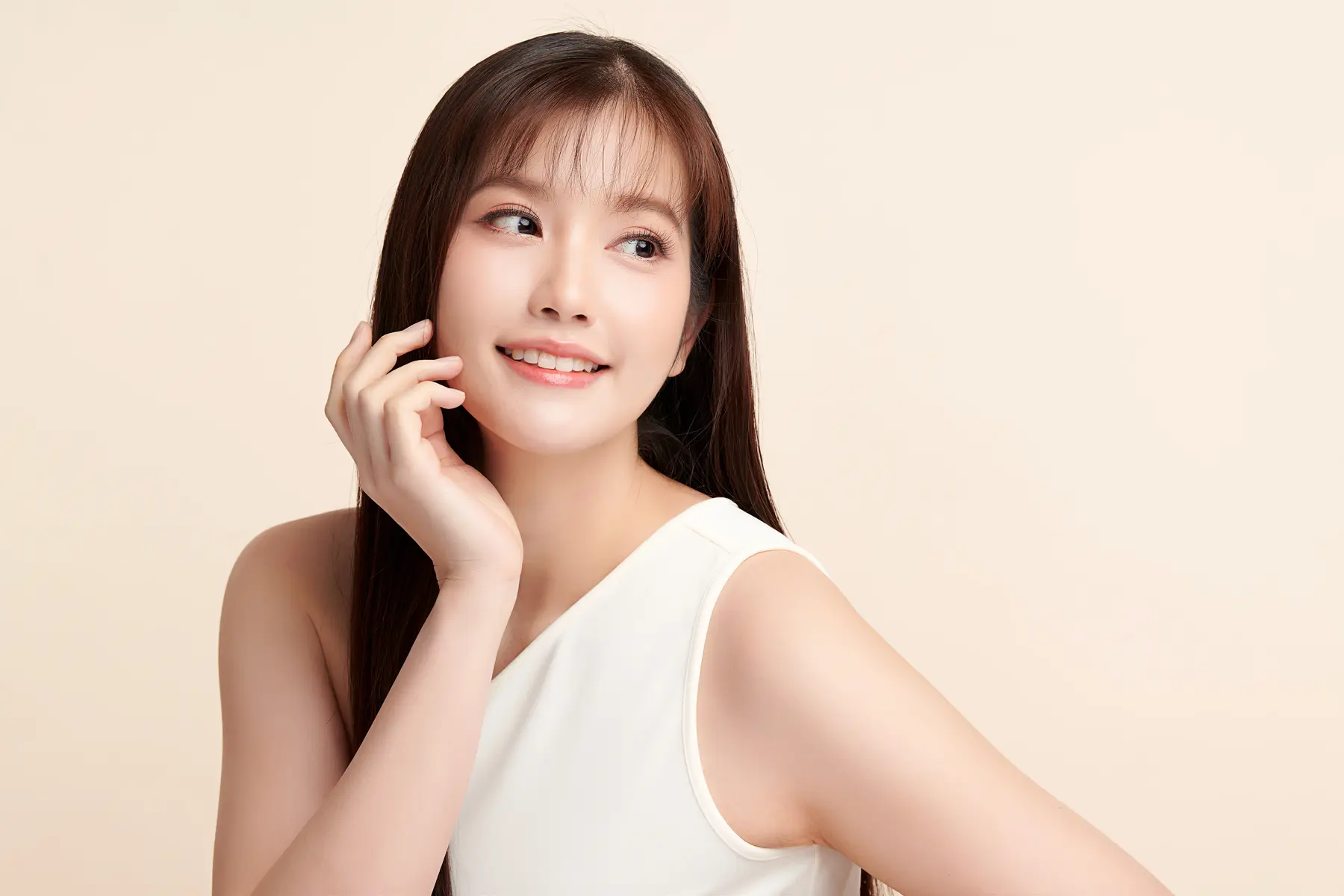 Skin Rejuvenation 1 Smiling woman with smooth skin touching face against a light background.